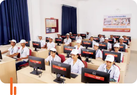 A group of trainees attending a session on 'Computer Accounting' at ICICI Satat Aajeevika Society in Jodhpur, Rajasthan. The image shows the trainees seated at computer workstations, focused on learning, wearing uniforms and caps, with a banner in the background related to the training program.