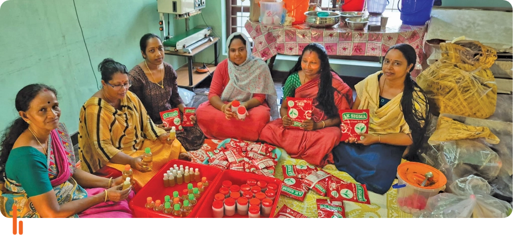 Members of the Sankeerthanam Kudumbashree Self-Help Group sitting together, displaying the products they have made. The image shows a group of women seated around a table with various products, including bottles and packaged items, indicating their collective efforts in product creation.